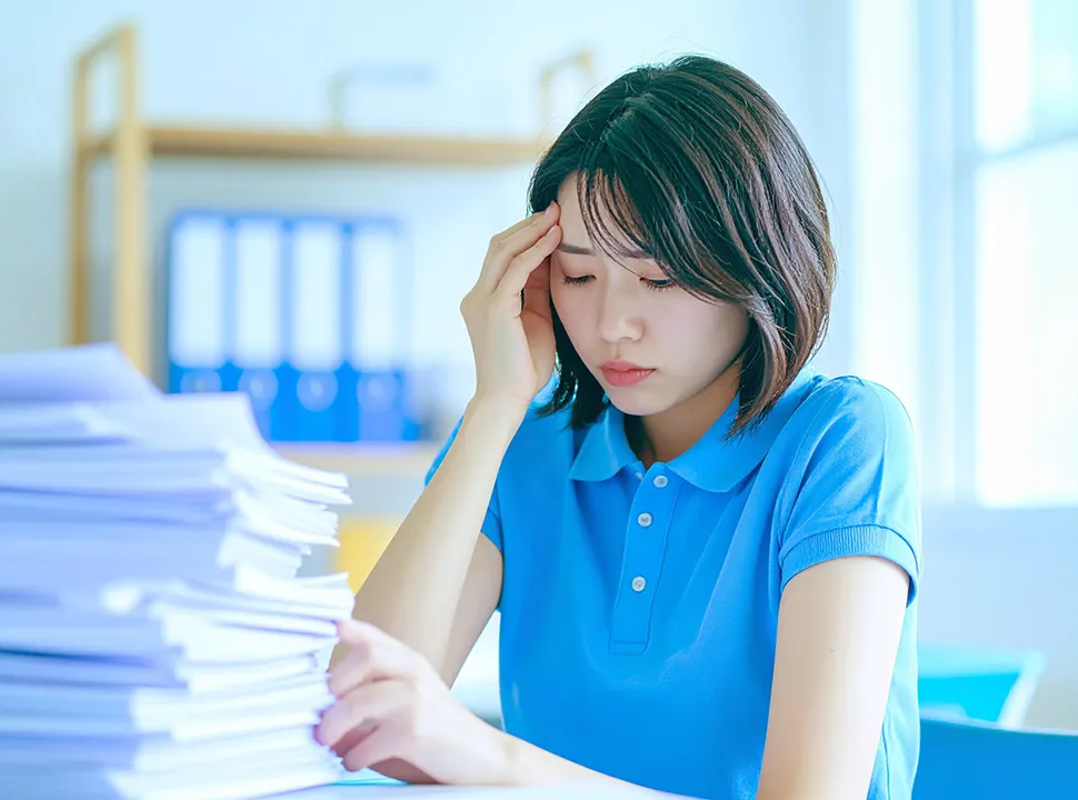 書類の山で悩んでいる女性